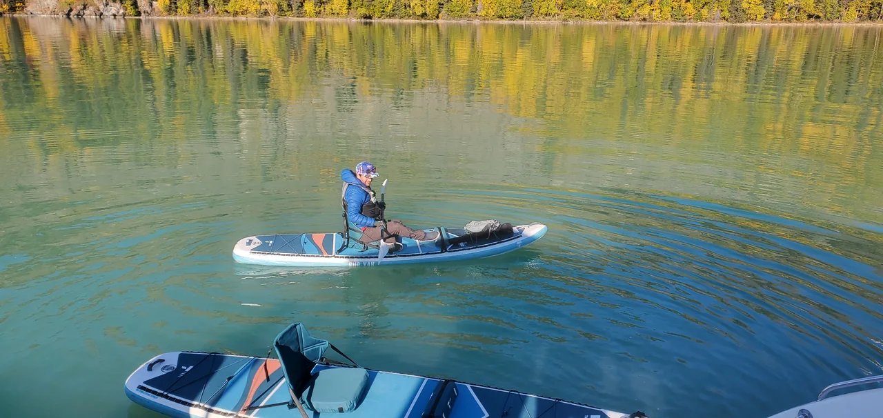 Paddleboarding on still water beside Lake Clark’s golden autumn shoreline