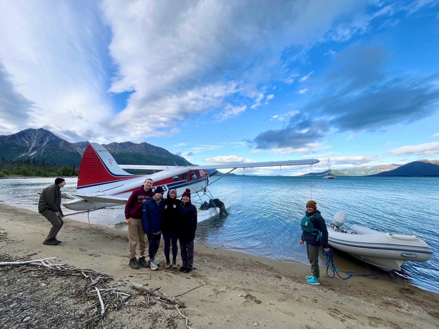 Guests beside a floatplane with Odyssey anchored in the background
