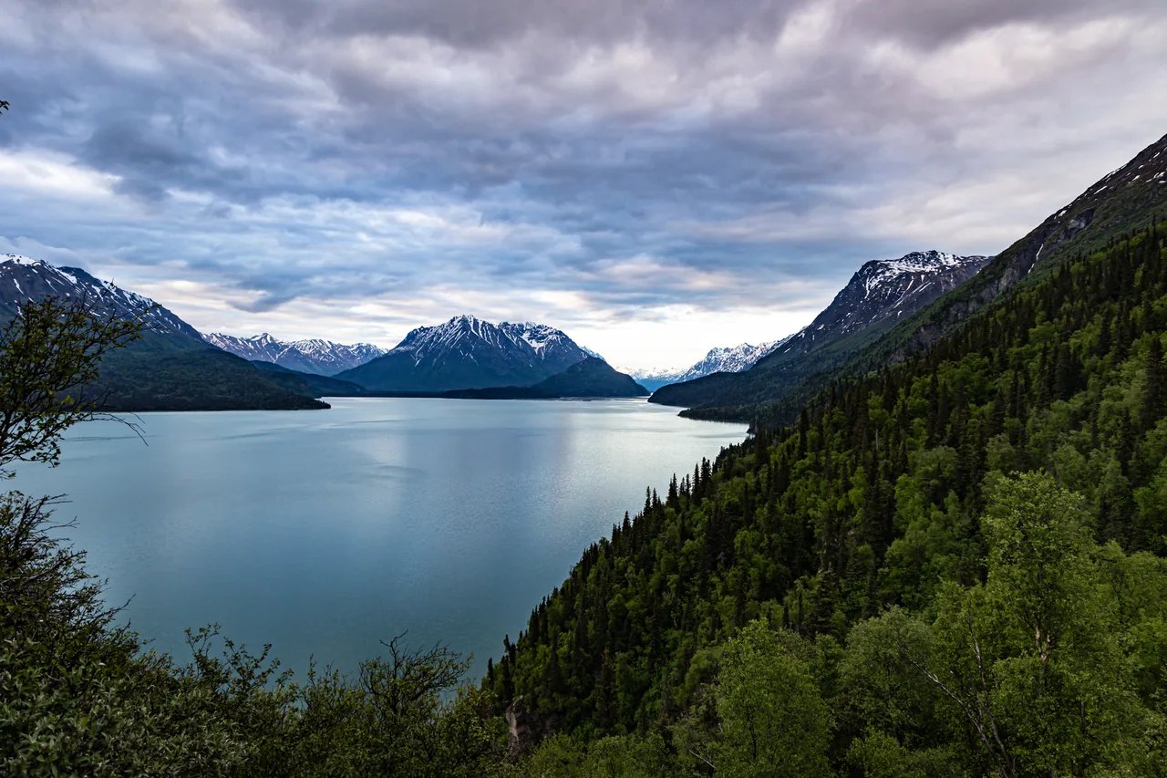 Lake Clark winding between forested hills and snow-dusted mountains